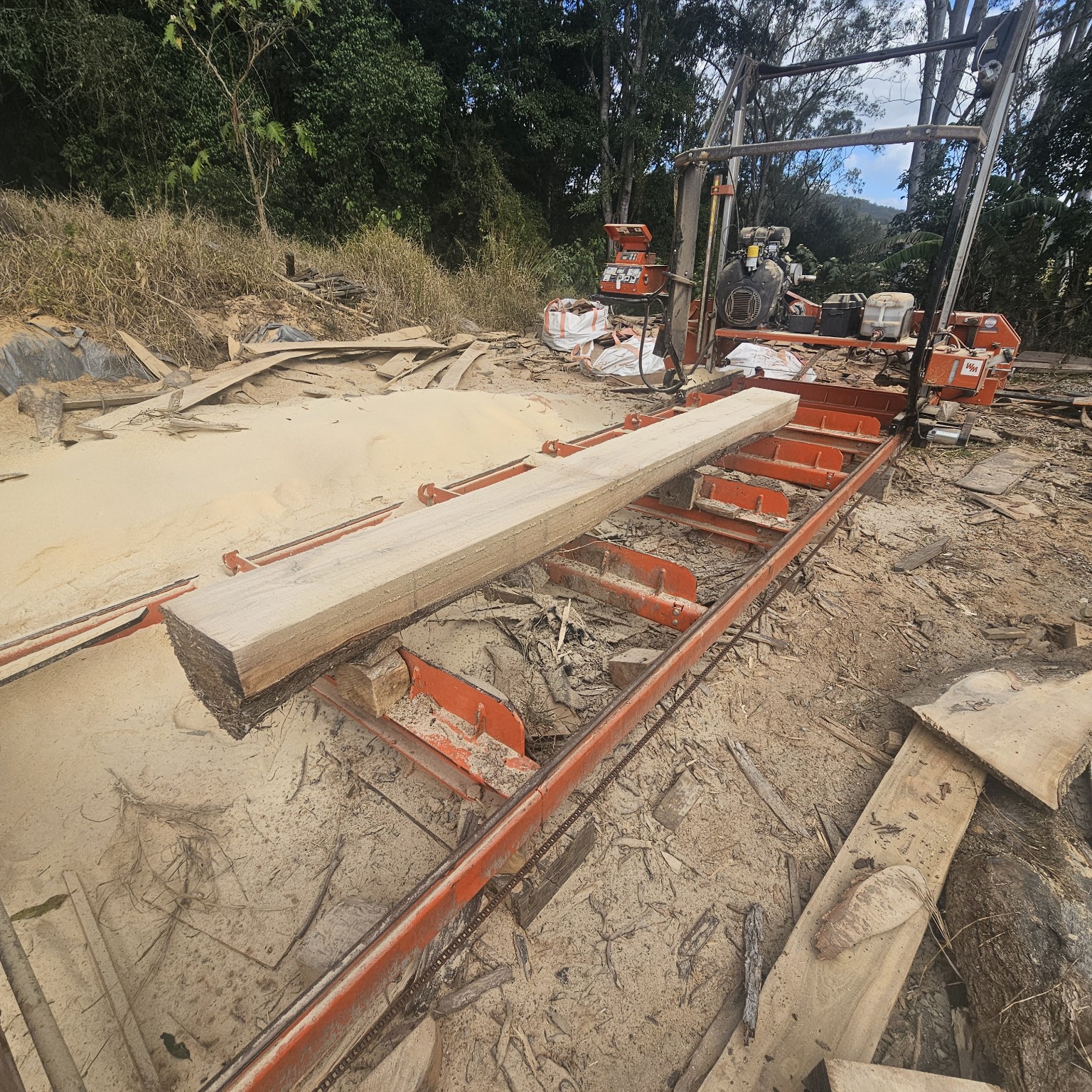 Sawn timber on the bed of an orange portable bandsaw mill