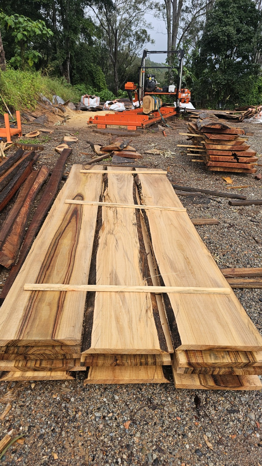 Sawn timber slabs stacked beside a portable sawmill